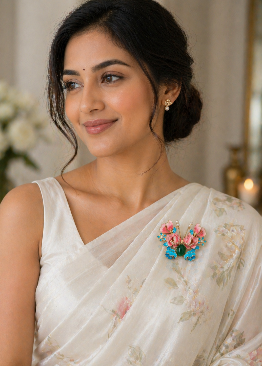 Woman wearing a white saree with floral butterfly brooch