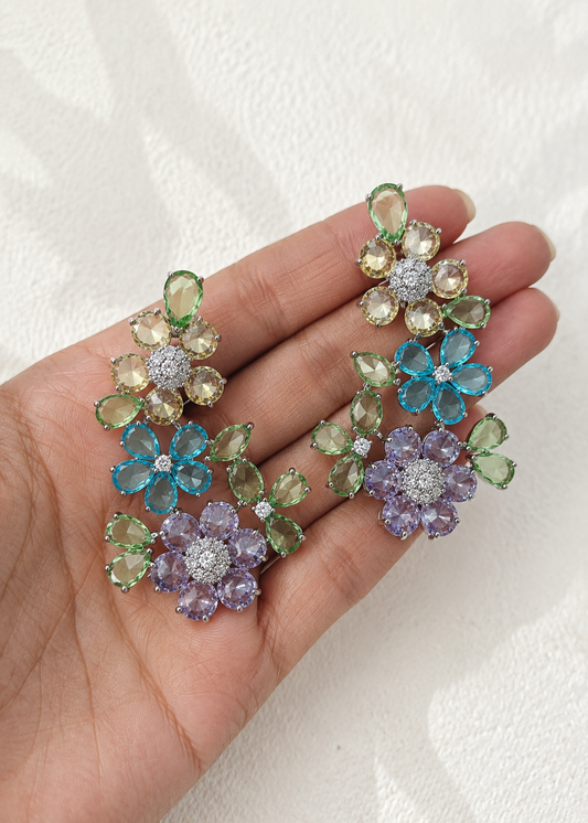 Close-up of Fleuré Pastel floral ear cuffs featuring multicolor crystal stones held on hand