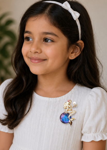 Young girl wearing a white blouse with a colorful brooch, against a neutral background