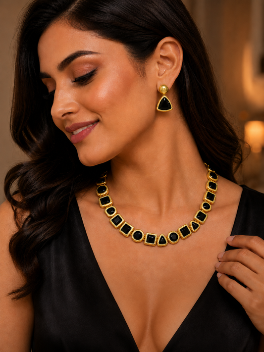 Woman wearing a gold and black necklace and earrings.