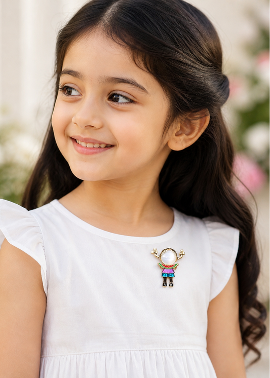 Young girl wearing a white dress with a decorative  girl brooch, standing outdoors with blurred flowers in the background.