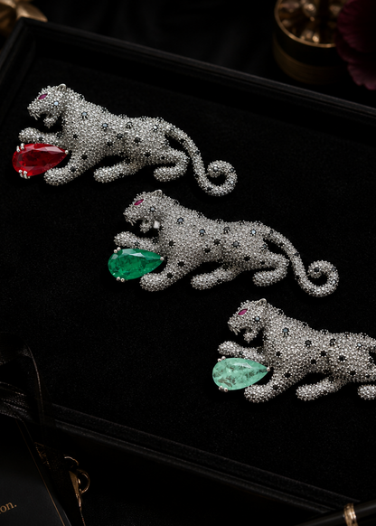 Three silver tiger brooches with gemstones on a black background