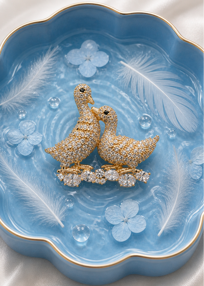Two diamond-studded duck brooch on a decorative blue background.