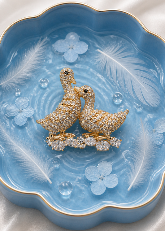 Two diamond-studded duck brooch on a decorative blue background.