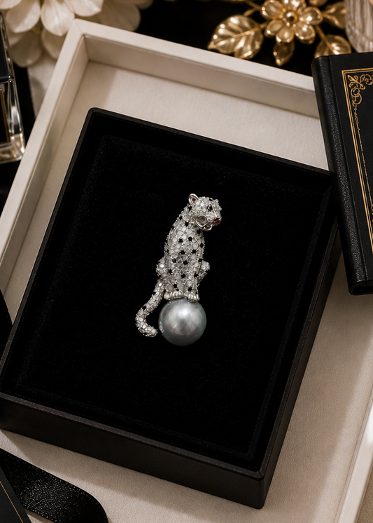 Silver Panther brooch with pearl on a black box surrounded by decorative items