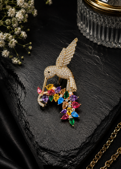 Rainbow Hummingbird Crystal Brooch displayed in a dark studio flat lay