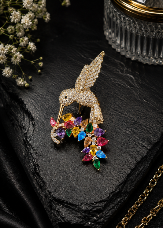 Rainbow Hummingbird Crystal Brooch displayed in a dark studio flat lay