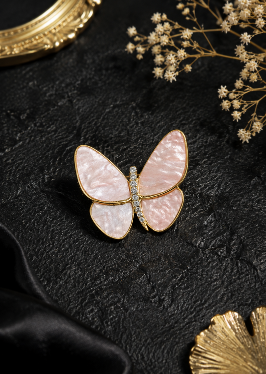 Blush Flutter Butterfly Brooch displayed in a dark studio flat lay