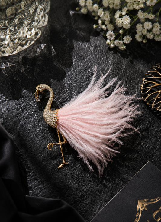 Blush Plume Flamingo Brooch displayed in a dark studio flat lay