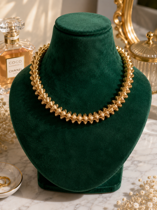 Golden Laurel Statement Necklace displayed on a green jewellery bust
