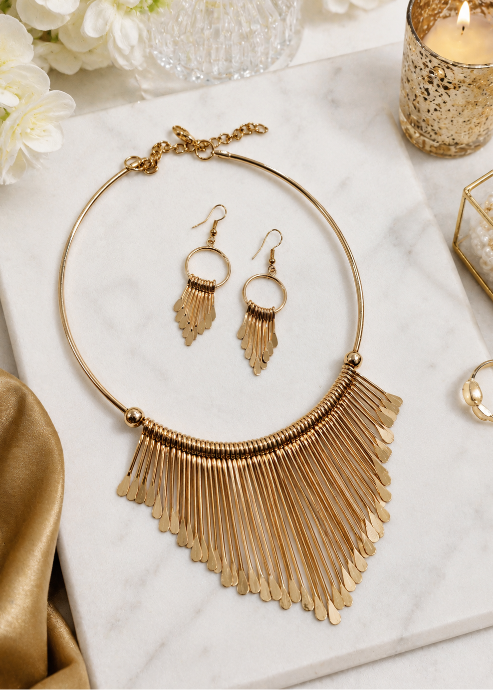 Aurora Gold Statement Necklace Set with matching fringe earrings displayed on marble background