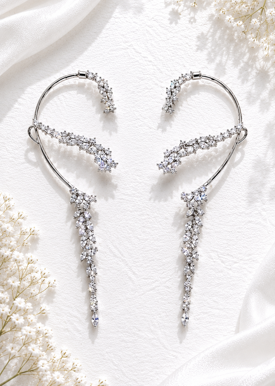 Silver crystal cascading statement ear cuffs with marquise cubic zirconia stones displayed on a white textured background.