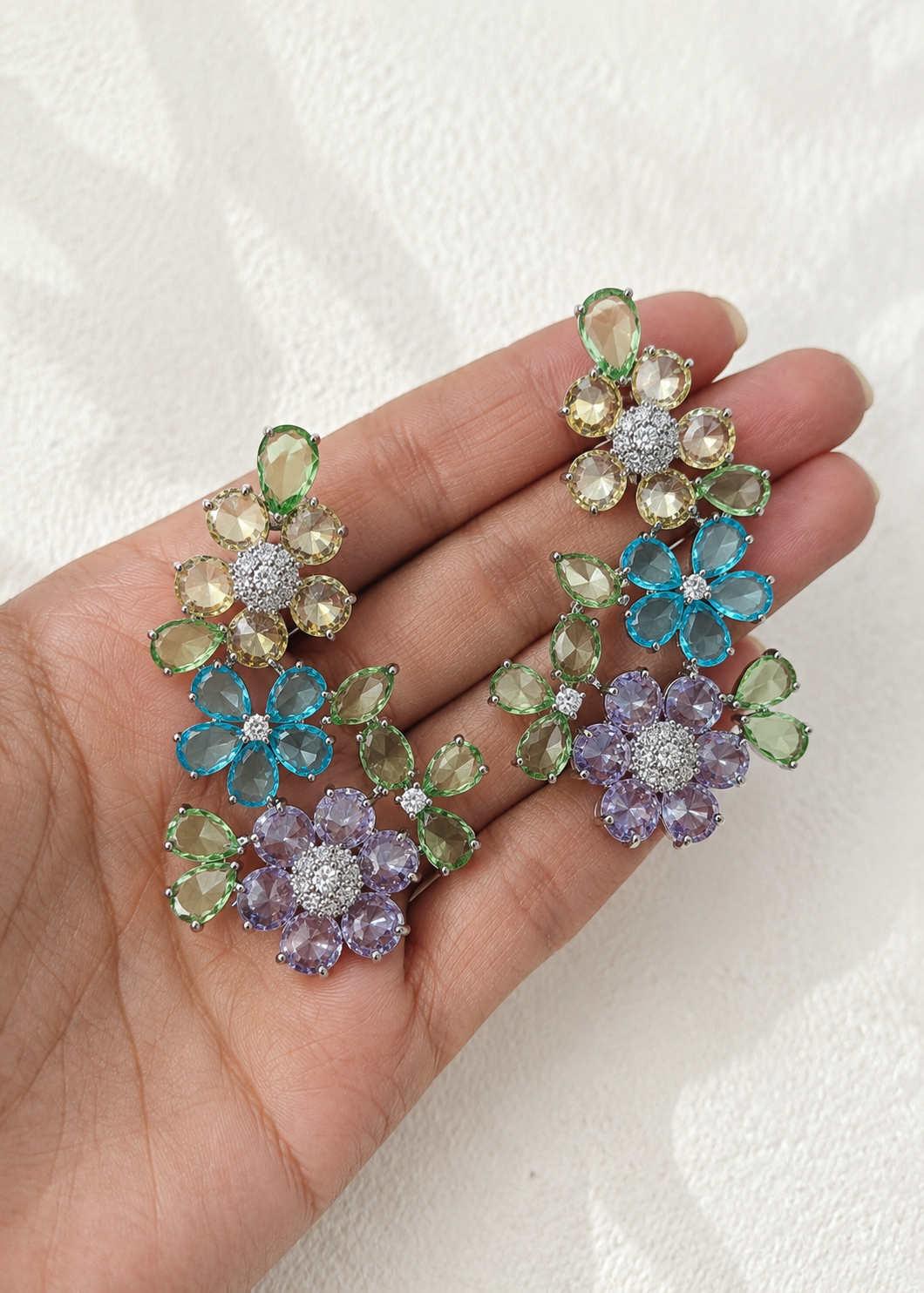 Close-up of Fleuré Pastel floral ear cuffs featuring multicolor crystal stones held on hand