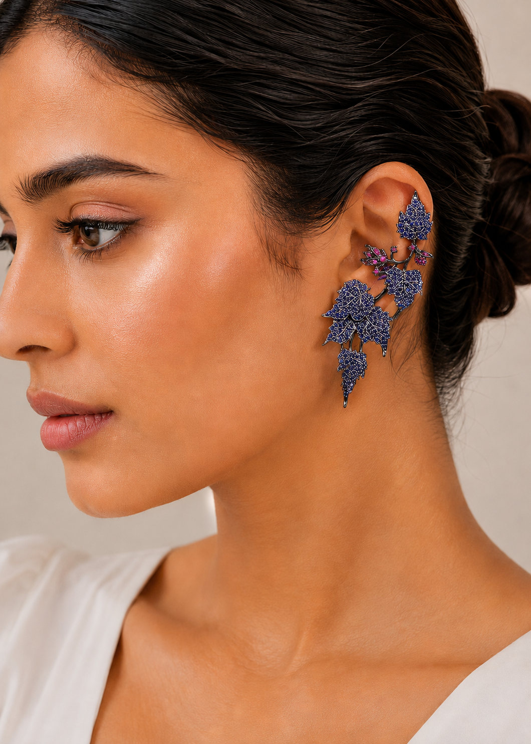 Model wearing Ivy Bloom Blue Ear Cuffs with sparkling blue stones in an elegant floral ear climber design