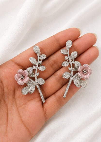 Silver floral ear cuffs with blush pink enamel flower and sparkling cubic zirconia leaves displayed on hand.