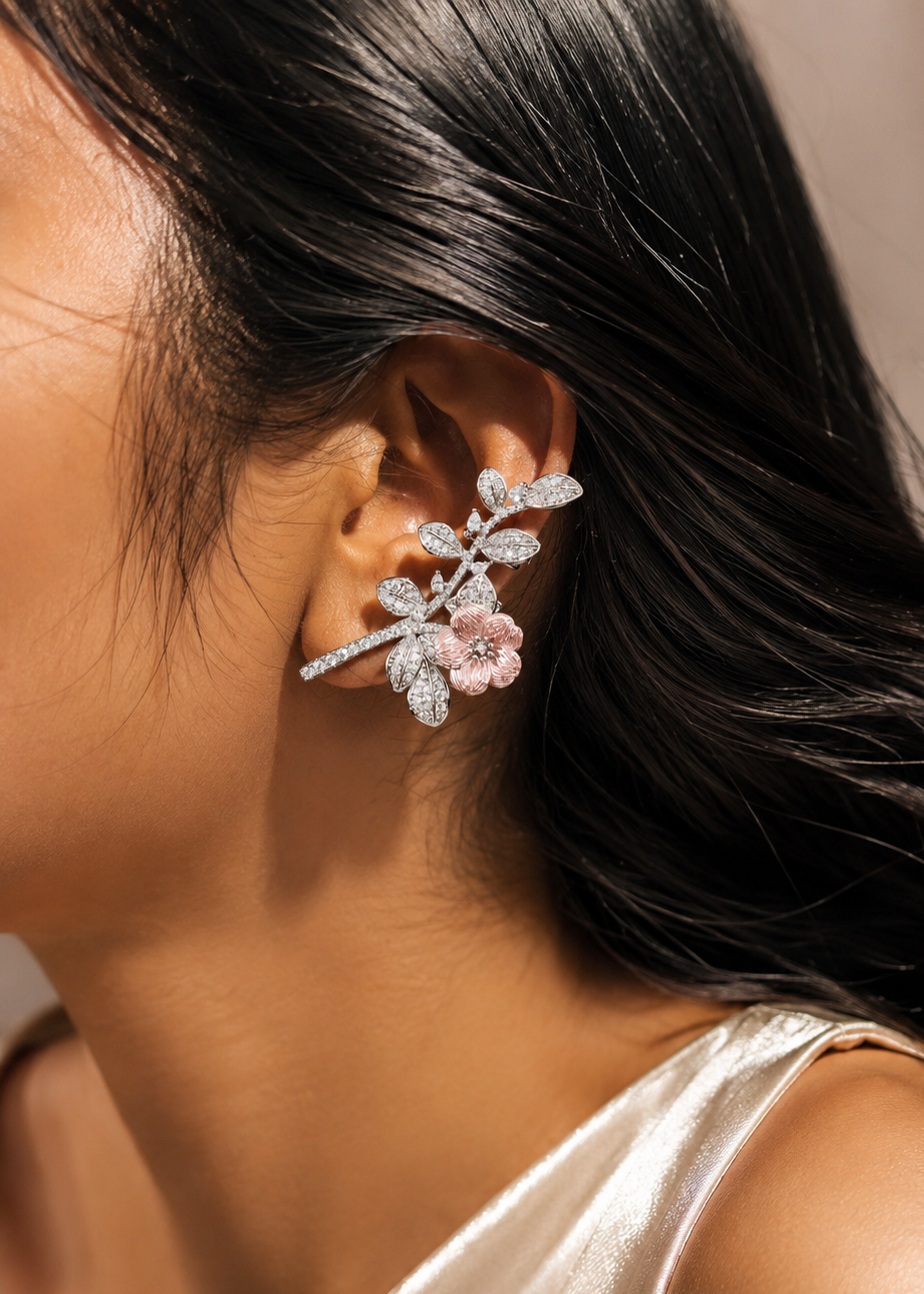 Close-up of woman wearing silver floral ear cuff with blush pink flower and sparkling crystal leaves.