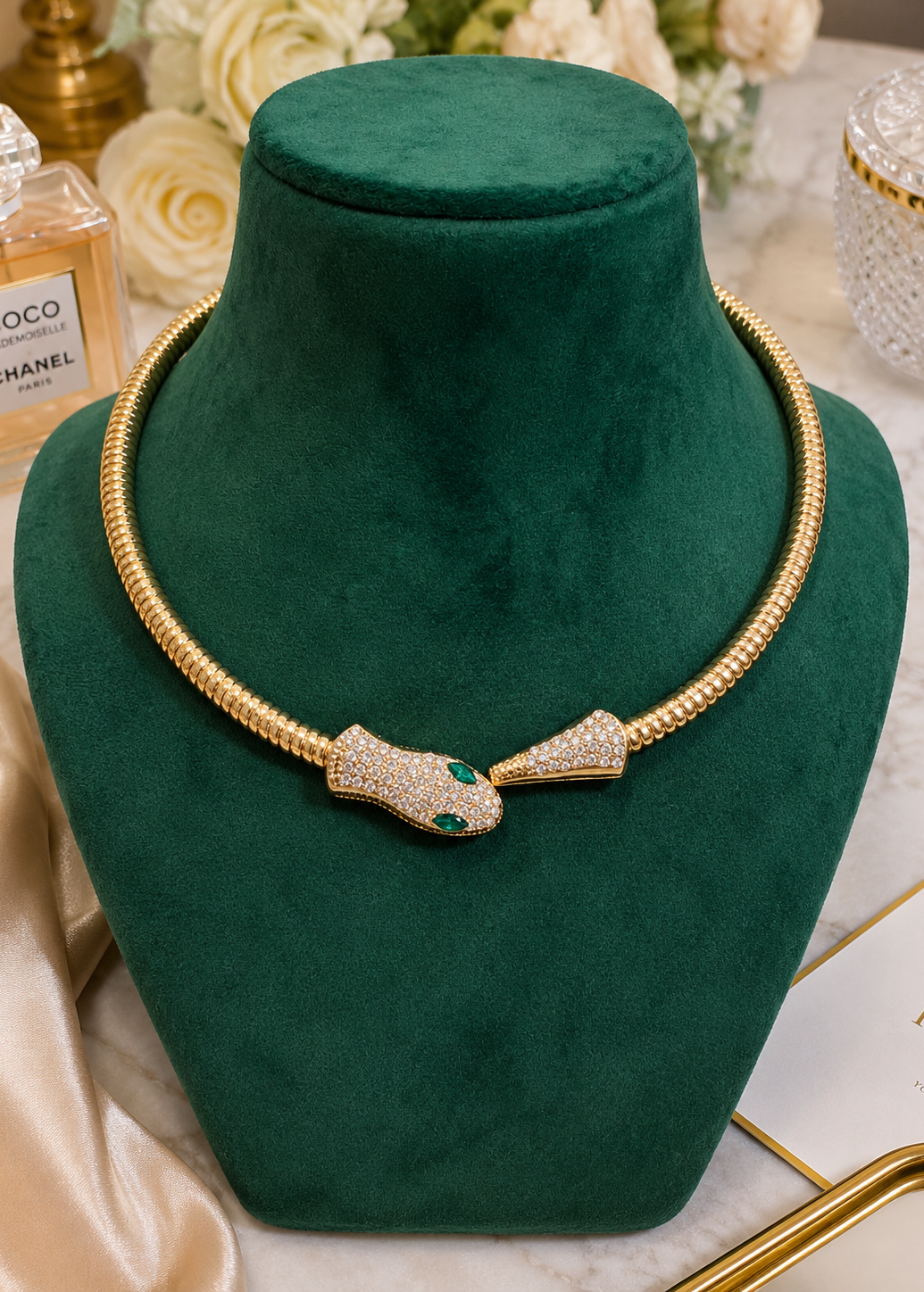 Serpentine Green Crystal Necklace displayed on a green velvet jewelry bust featuring gold snake design with crystal detailing.