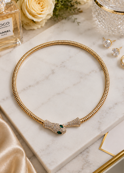 Serpentine Green Crystal Necklace with gold finish, sparkling white crystals and emerald green crystal eyes displayed on marble.