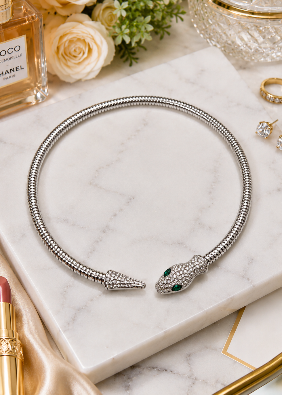 Serpentine Silver Crystal Necklace featuring sparkling white crystals and emerald green eyes displayed on a marble surface.